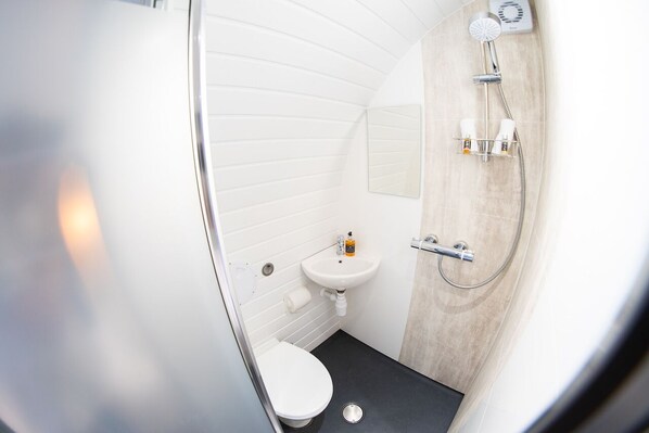 A compact bathroom with a white toilet, a sink, and a shower.