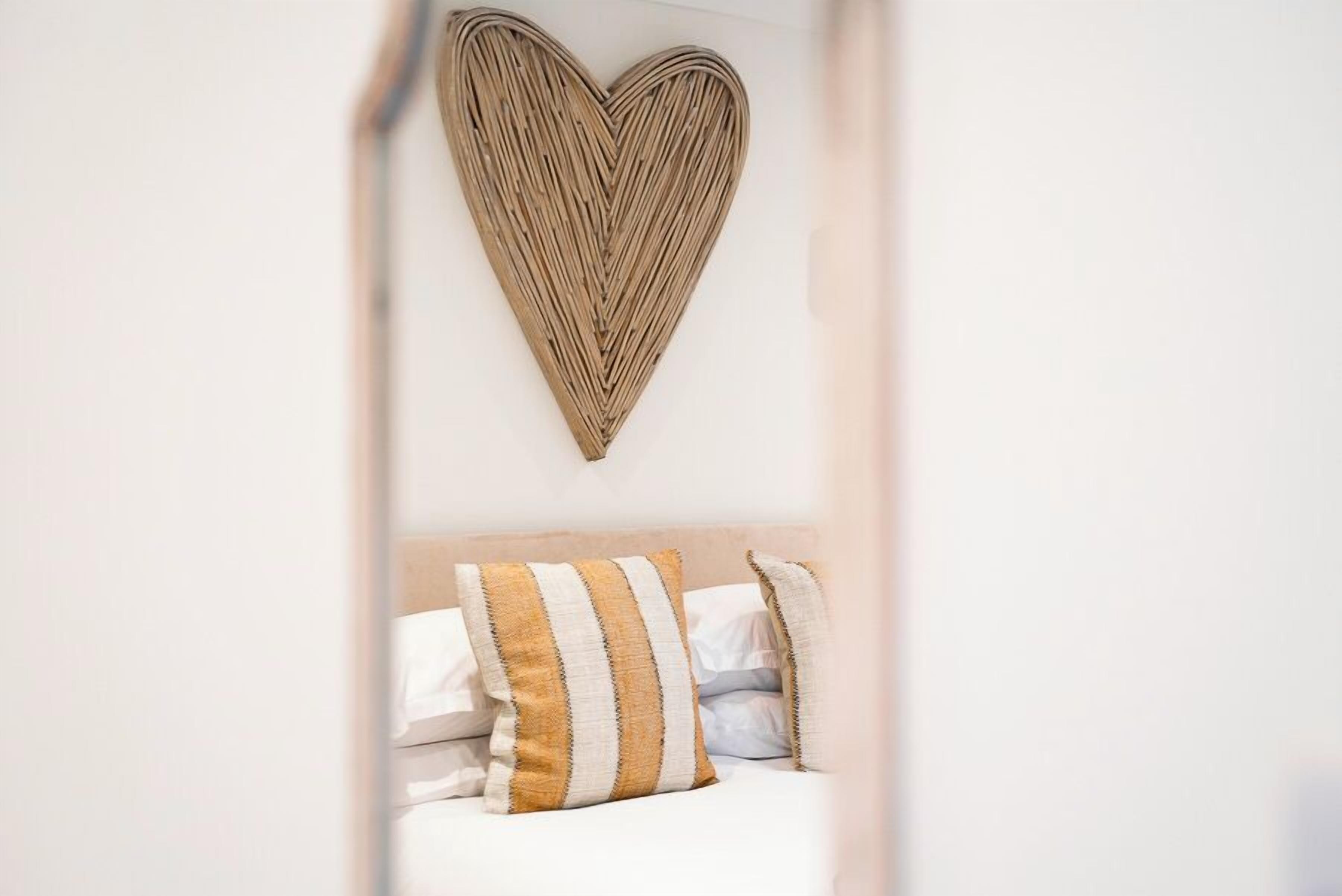 A bedroom with a bed, pillows, and a heart-shaped wall decoration.