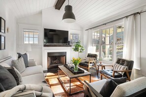 Una sala de estar moderna con chimenea, asientos cómodos y ventanas amplias.