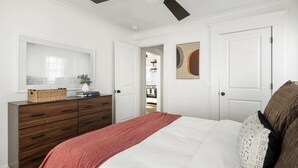 A bedroom with a bed, a dresser, a ceiling fan, and a door leading to a closet. - Ready Aim (Atlanta)
