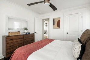 Un dormitorio con cama, cómoda, ventilador de techo y puerta que da a un armario.