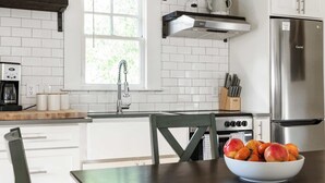 A modern kitchen with white cabinets, a stainless steel refrigerator, and a bowl of fruit on the counter. - Ready Aim (Atlanta)