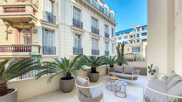 A spacious outdoor area with potted plants, a sofa, and a chair. - N&J - PALMIERS TERRASSE - Central - Terrace (Niza)