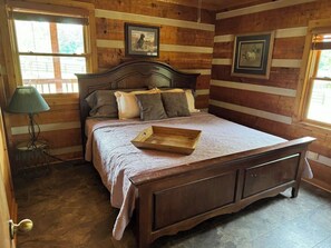 A wooden-paneled bedroom with a bed, a bedside table, and a lamp. - Harpeth Moon Summary: (Kingston Springs)