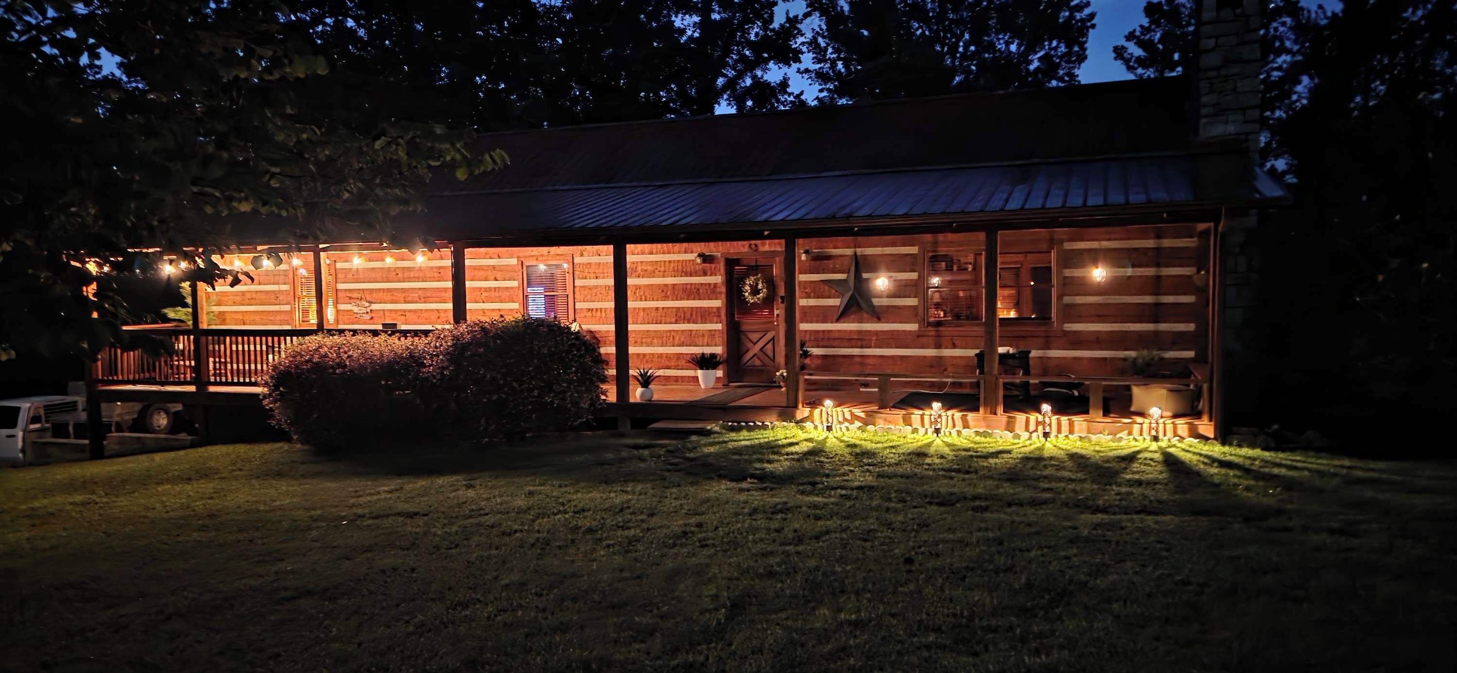 A wooden cabin with a porch, large windows, and a star decoration on the wall.
