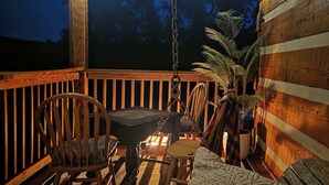 A wooden deck with a table and chairs, a hanging chair, and a potted plant.