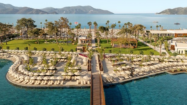 A resort with a pool, lounge areas, and a view of the sea.