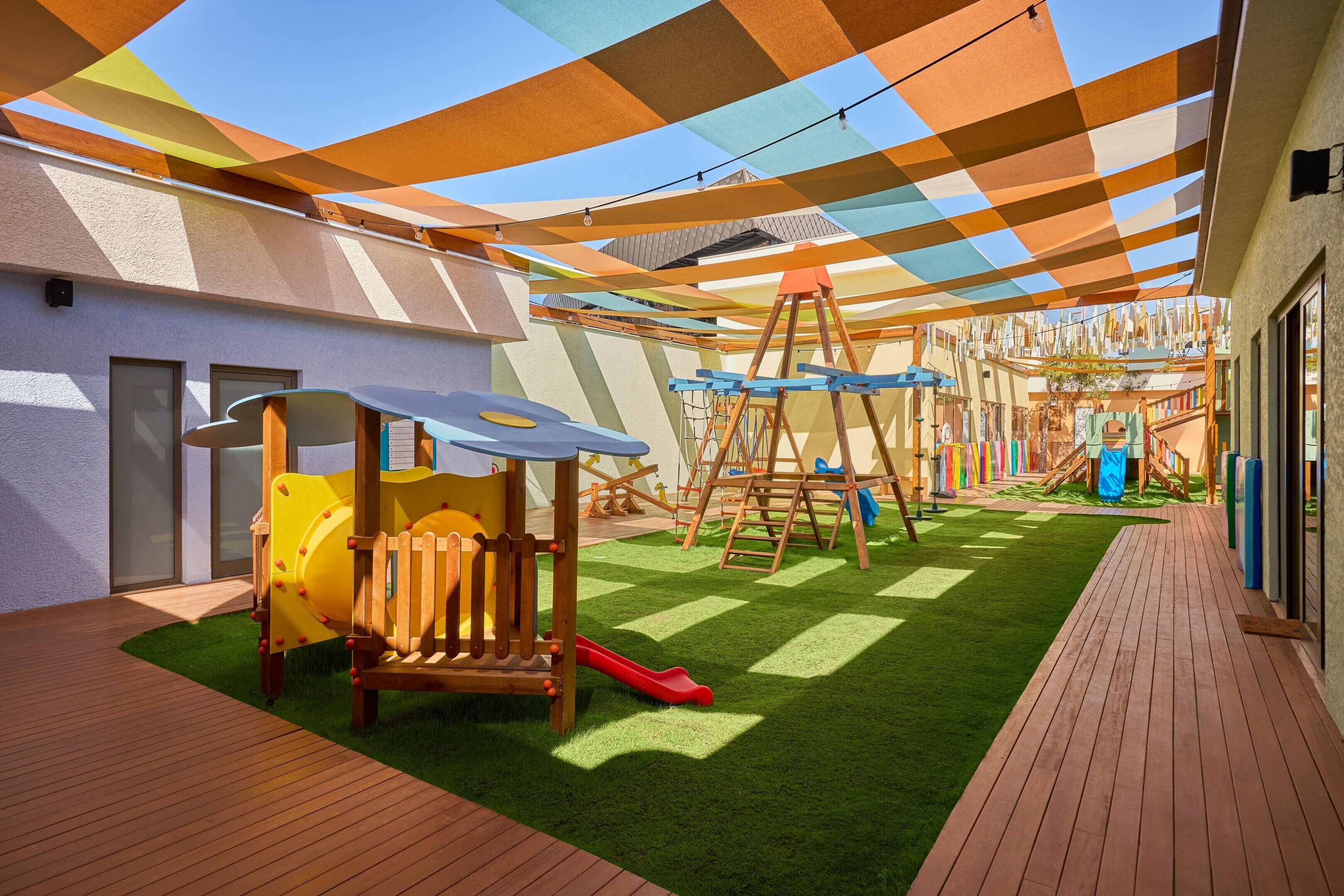 A children's play area with a slide, climbing structures, and a wooden deck.