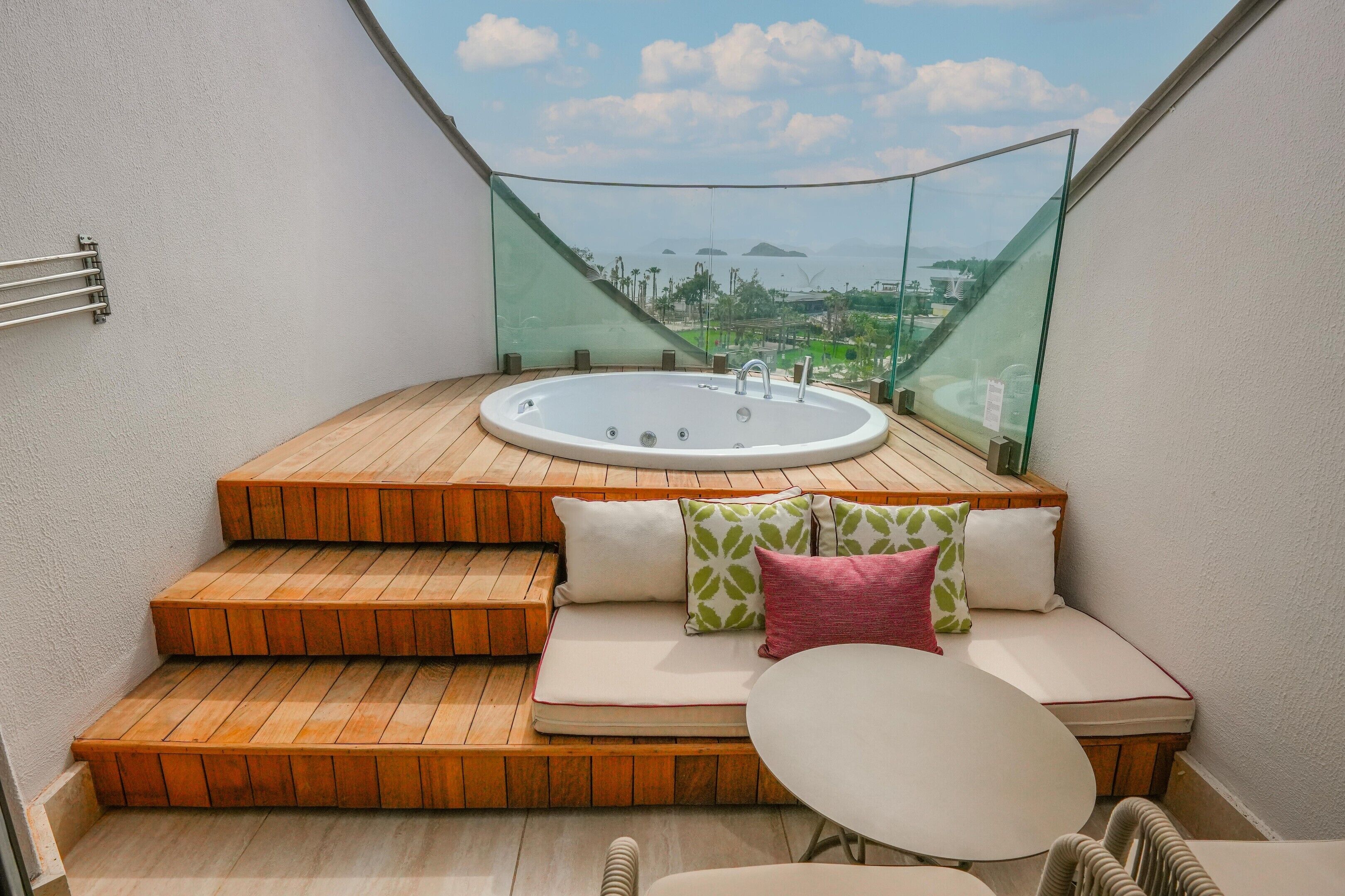 A hot tub with a wooden deck and a seating area with cushions.