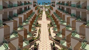 Un hôtel moderne à l’architecture symétrique, doté de nombreux balcons, d’une cour intérieure agrémentée de plantes et offrant une vue sur la mer.