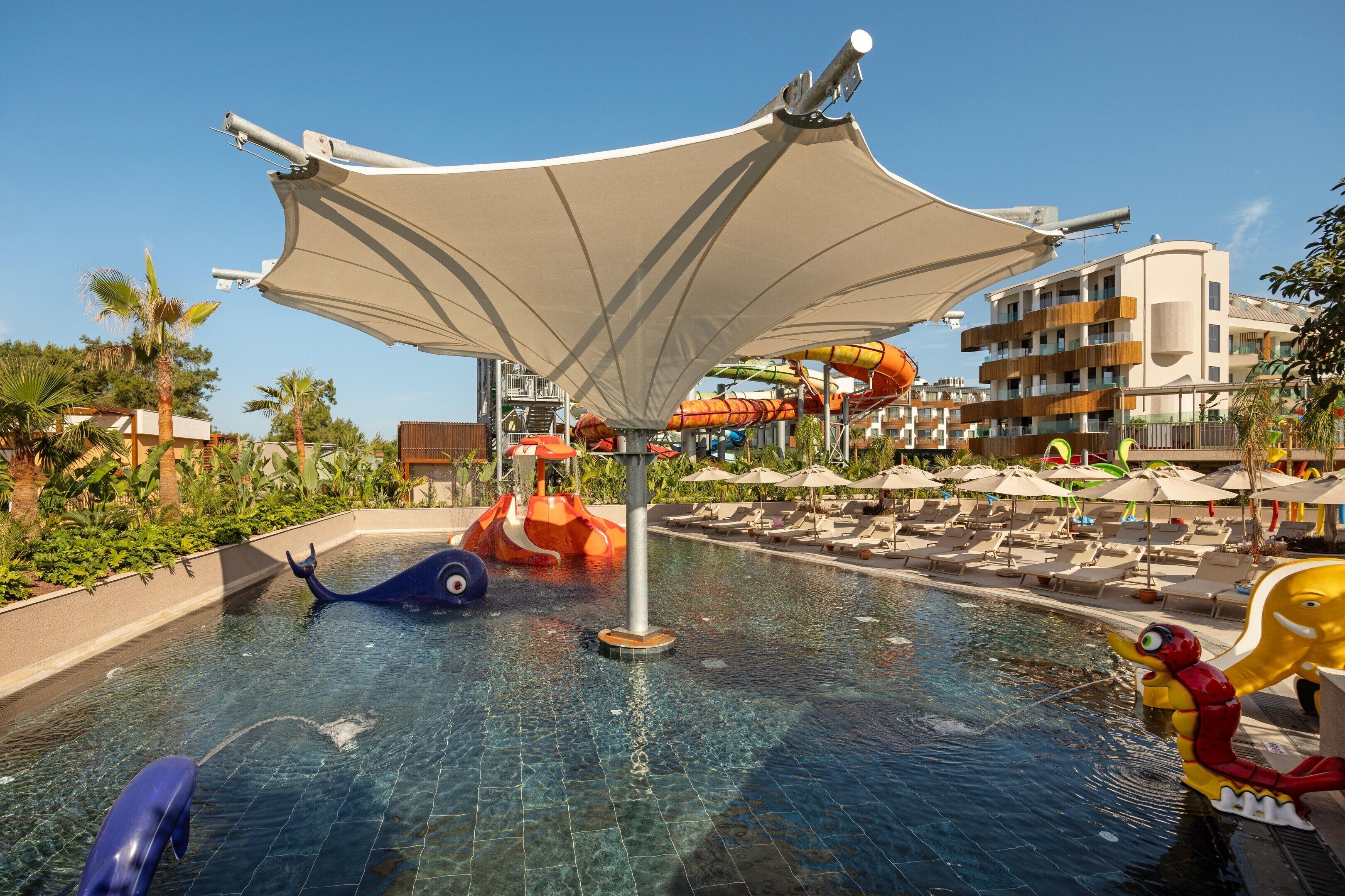 Un área de piscina con toboganes, sillas de descanso y sombrillas.