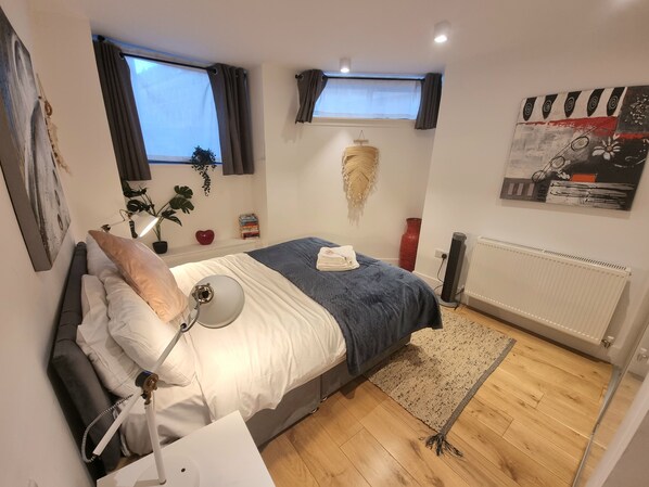 A bedroom with a bed, bedside lamp, and a radiator. - Large Duplex 7 Adults at London Bridge (London)