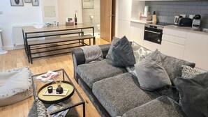 Un salon moderne avec un canapé gris, une table basse et un coin repas équipé de bancs.