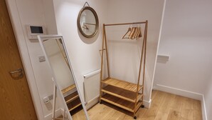 A room with a wooden floor, a radiator, a mirror, and a wooden clothes rack. - Large Duplex 7 Adults at London Bridge (London)
