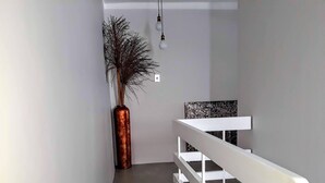 A modern interior with a concrete floor, white railing, and a large vase with dried branches. - Sea Point; Secure 100m² top floor 2 bed apartment with mountain views (Sea Point)