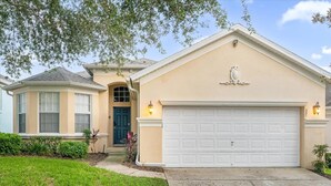 A single-story house with a beige facade, a dark blue front door, and a white garage door. - Luxe 8-Guest Villa Davenport | Stunning Design (Davenport)