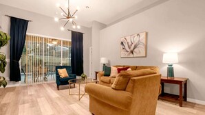 A modern living room with a sofa, armchair, and a dining table. - Luxe 8-Guest Villa Davenport | Stunning Design (Davenport)