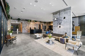 A spacious lobby with a reception desk, seating area, and a large wall with a clock.