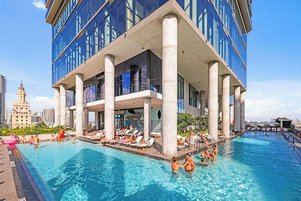 A modern building with a rooftop pool area, surrounded by a cityscape.