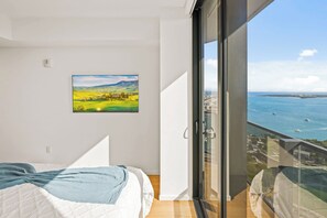 Una camera da letto con un'ampia finestra, un letto, un quadro e vista sul mare.