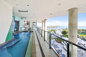 A swimming pool with a glass barrier, a view of a cityscape, and a balcony with outdoor seating. - Bright Resort Style 1BR Heart of Miami Downtown (Miami)