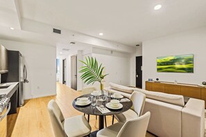 A modern dining area with a round table set for four, a sofa, and a large window with a view of a green landscape. - Bright Resort Style 1BR Heart of Miami Downtown (Miami)