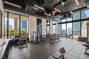 Una palestra con attrezzatura per sollevamento pesi, ampie finestre e vista sulla città.