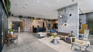 En rummelig lobby med en receptionsdisk, siddeområder og en stor væg med et ur.