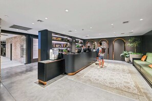 A modern reception area with a counter, seating area, and a brick wall. - Bright Resort Style 1BR Heart of Miami Downtown (Miami)