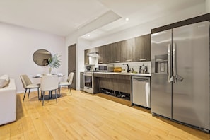 A modern kitchen with a built-in oven, microwave, and refrigerator, a dining area with a round table and chairs, and wooden flooring. - Bright Resort Style 1BR Heart of Miami Downtown (Miami)