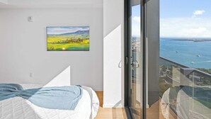 Et soveværelse med seng, et billede og en balkon med udsigt over havet.