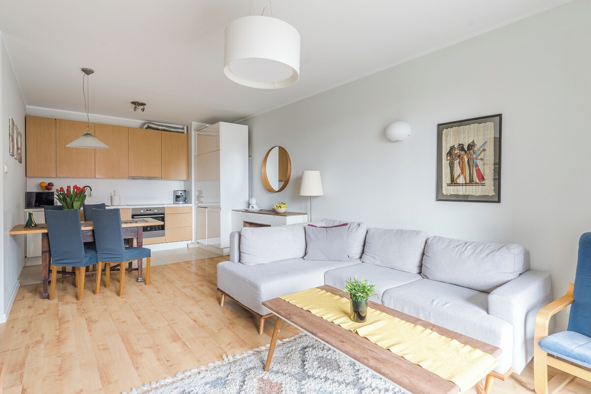 A modern living room with a sofa, coffee table, and dining area.