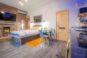 Une chambre moderne avec un mur en briques, un lit, un bureau et un téléviseur.