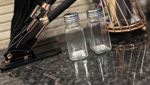 Una encimera de cocina con un bloque de cuchillos, saleros y una cuchara de madera.