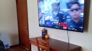 Une pièce avec une table en bois et un téléviseur fixé au mur, diffusant un événement sportif.