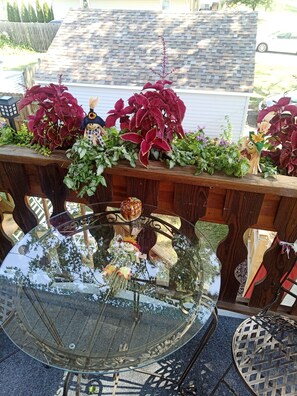 A round glass table with a decorative centerpiece, surrounded by wooden furniture and potted plants. - Simple Stay for Family and Friends, 2-bedroom upstairs apartment in Boardman. (Youngstown)