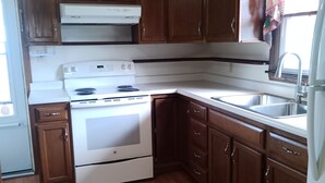 Une cuisine avec des meubles en bois, une cuisinière blanche et un évier.