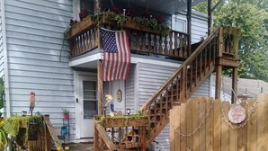 Une maison à deux étages avec un escalier en bois, une pancarte de bienvenue et un drapeau américain.