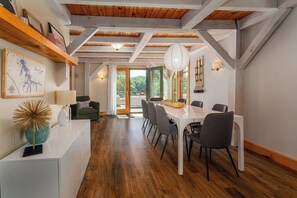 A modern interior with a dining area, wooden beams, and a view to the outdoors.