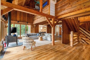 A spacious wooden interior with a fireplace, a sofa set, and a dining area.