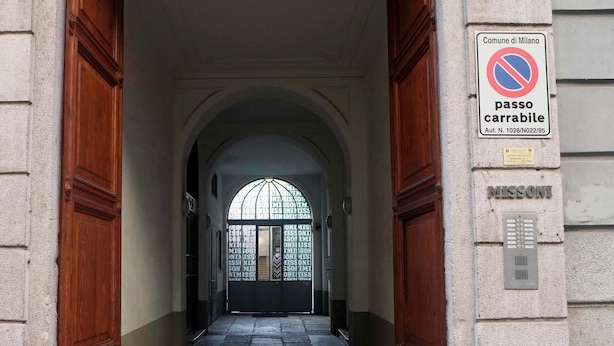 A corridor with a no parking sign, a door labeled "MISSONI", and a window with a view of the street.