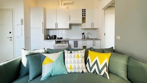 A modern kitchen with white cabinets, a built-in oven, and a coffee machine.