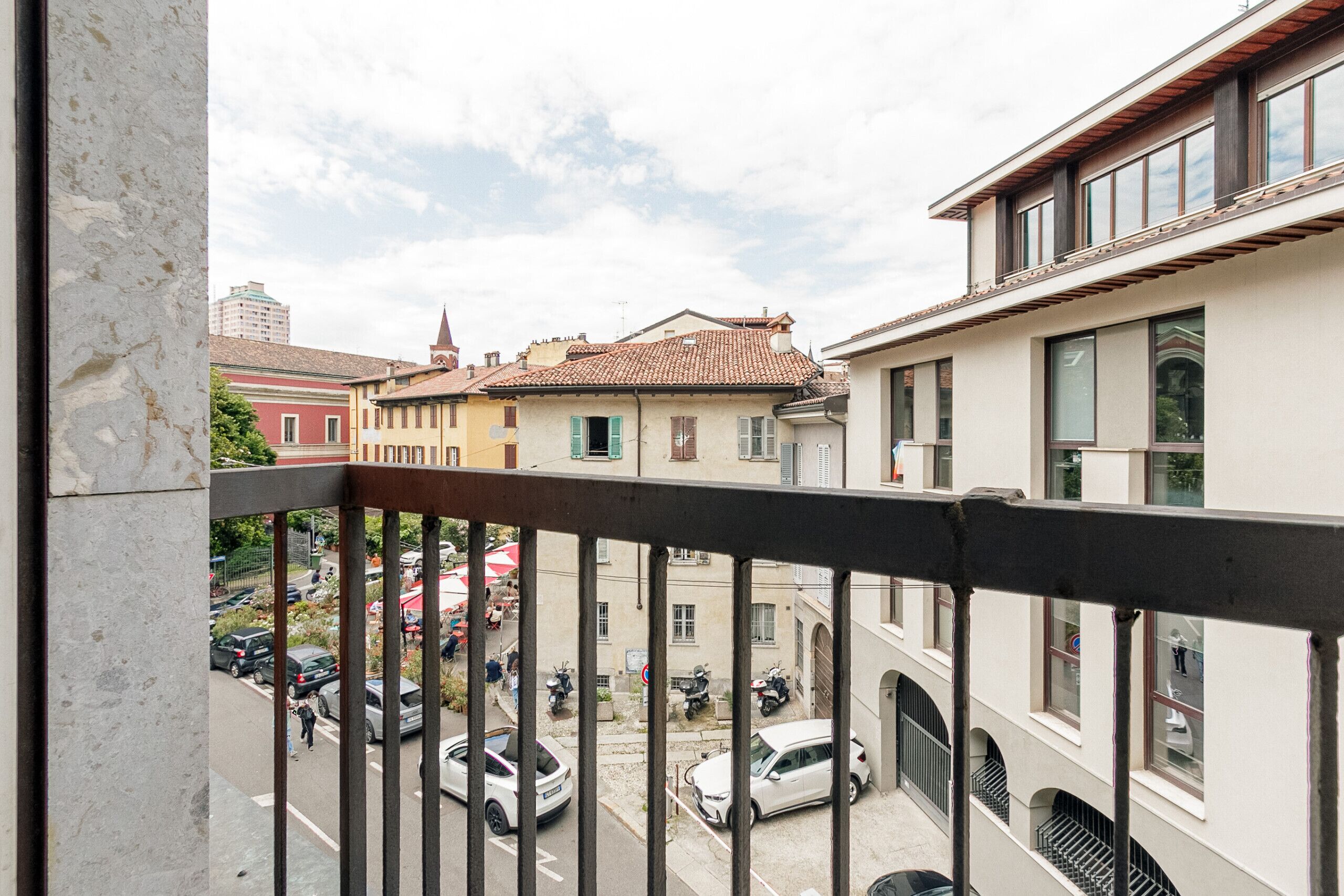 A balcony with a view of a street with parked cars and buildings.