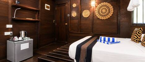 A hotel room with a bed, a minibar, a wall-mounted air conditioner, and decorative wall panels.