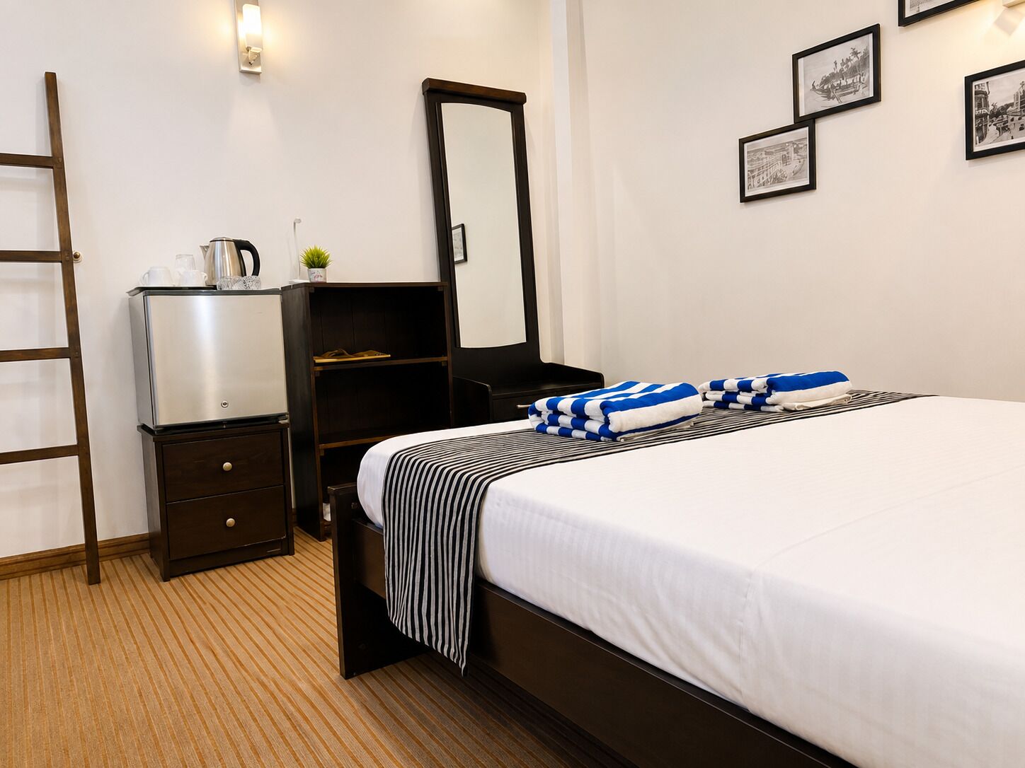 Ein Hotelzimmer mit Bett, Nachttisch, Schminktisch und Spiegel, an der Wand befinden sich gerahmte Bilder.