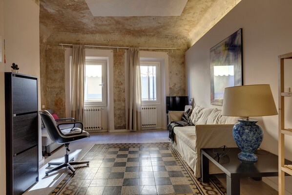 Ein Zimmer mit Schachbrettmuster, einem Sofa, einem Sessel, einer Lampe und einem Fernseher.