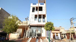 A multi-story building with a central entrance, a staircase, and a small tree in front. - Hotel Aishwarya Inn (Jaipur)