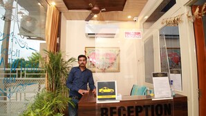 A reception desk with a "RECEPTION" sign, a "TAXI SERVICE" sign, and a "NO SMOKING" sign. - Hotel Aishwarya Inn (Jaipur)