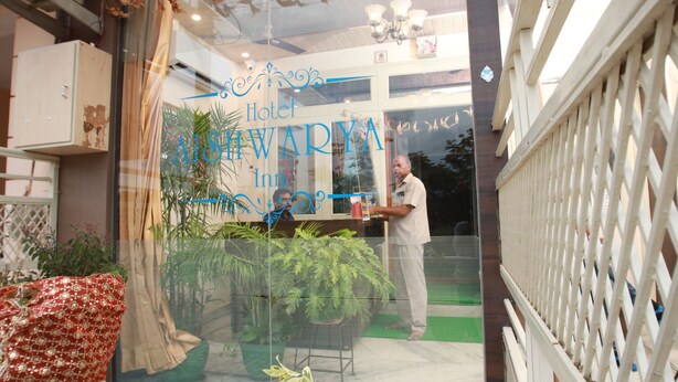 A hotel entrance with a glass door, a sign reading "Hotel Alwiwara Inn," and a person standing near the door. - Hotel Aishwarya Inn (Jaipur)