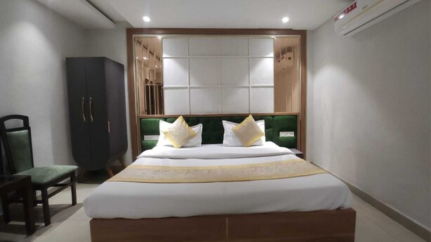 Una camera d'albergo con un letto grande, una testiera imbottita verde e un armadio.
